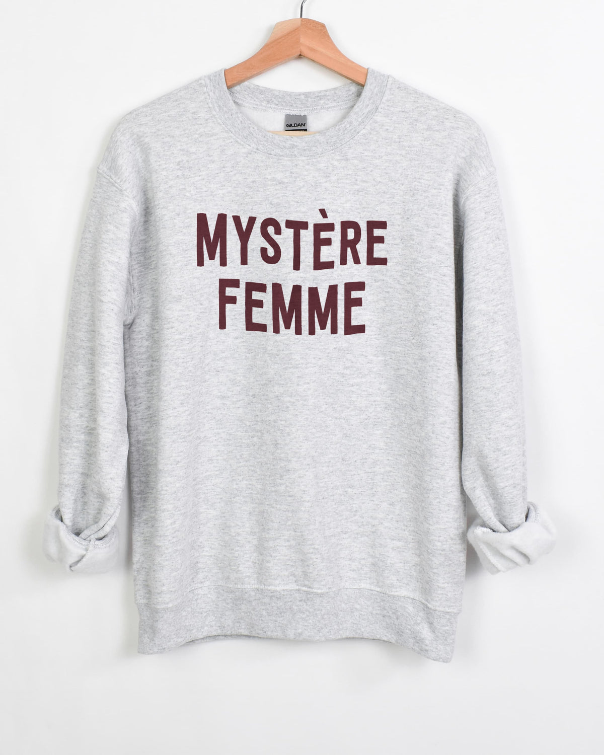 Mystère Femme sweatshirt in ash with burgundy lettering on a hanger, sleeves rolled